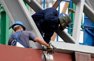 Two construction workers putting together a metal frame