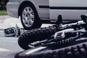 Motorcycle on its side, car side view mirror on the pavement after an accident