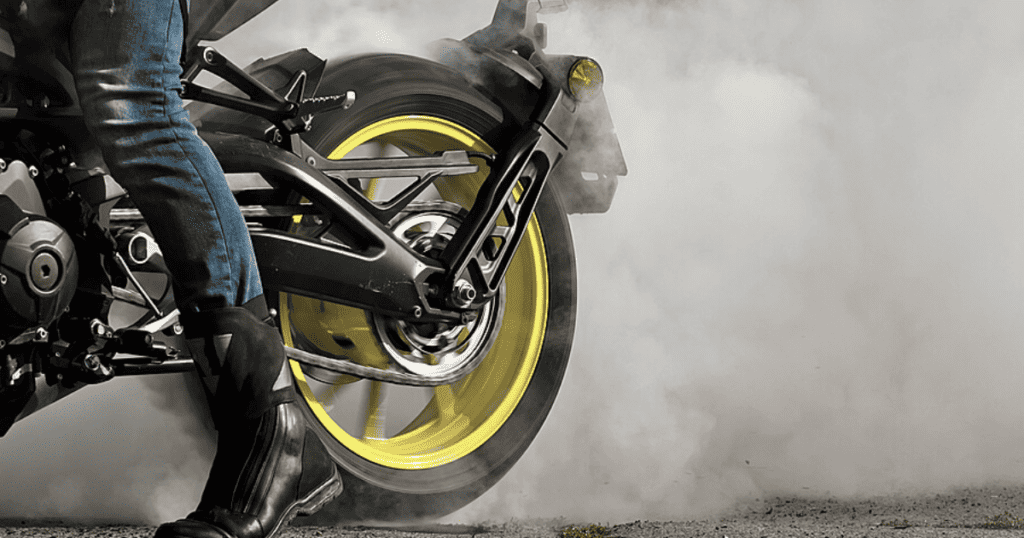 Motorcycles rider performing a burnout their rear yellow-rimmed custom tire