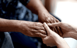 A younger person holding the hands of an older person