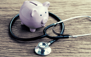 stethoscope and piggy bank with wood table background
