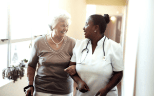 Older woman walking arm in arm with a medical professional at a nursing home