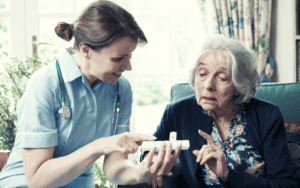 Nursing home employee assists an elderly woman with her medication