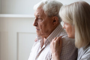 Man in nursing home being comforted by female family member