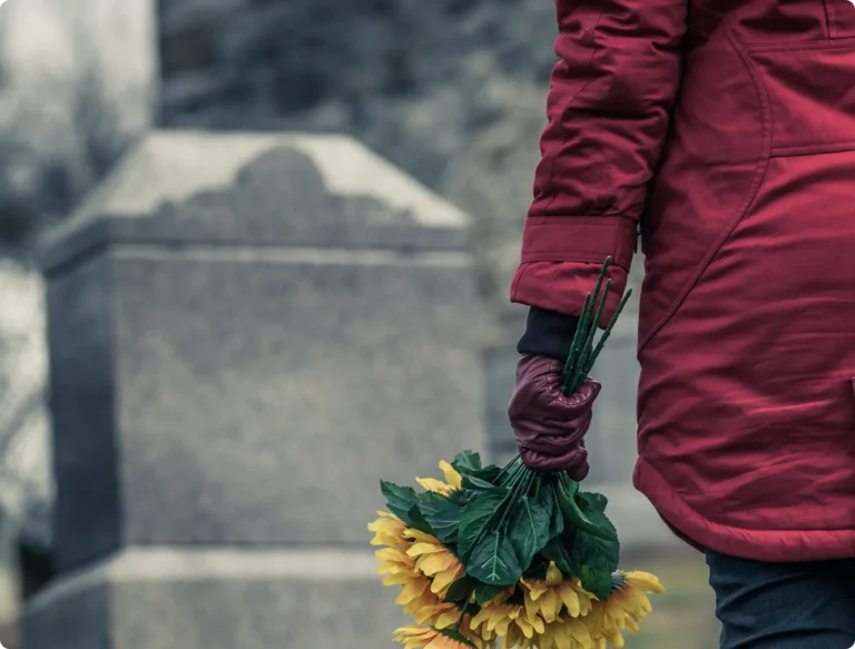 Women putting flowers on graveston
