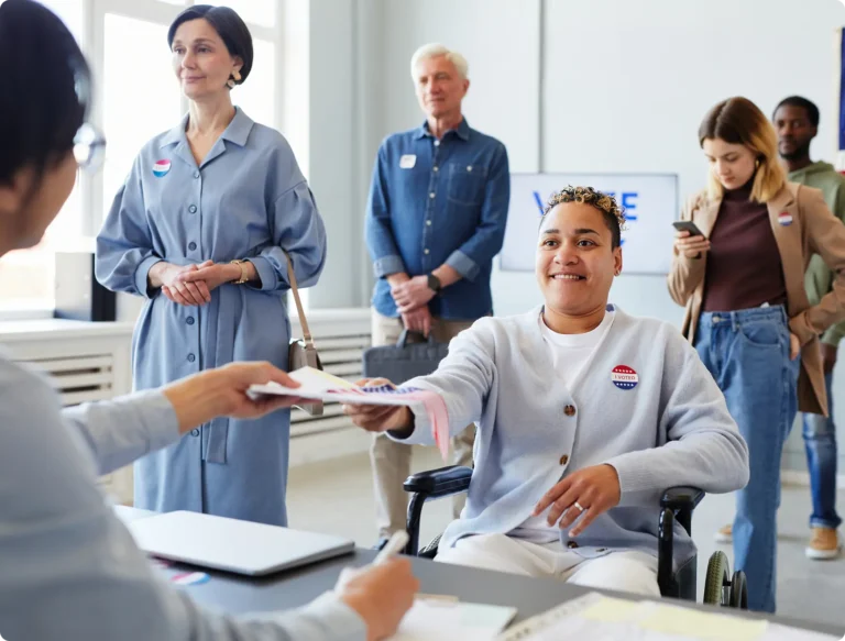 Women in wheelchair handing in paperwork to front desk
