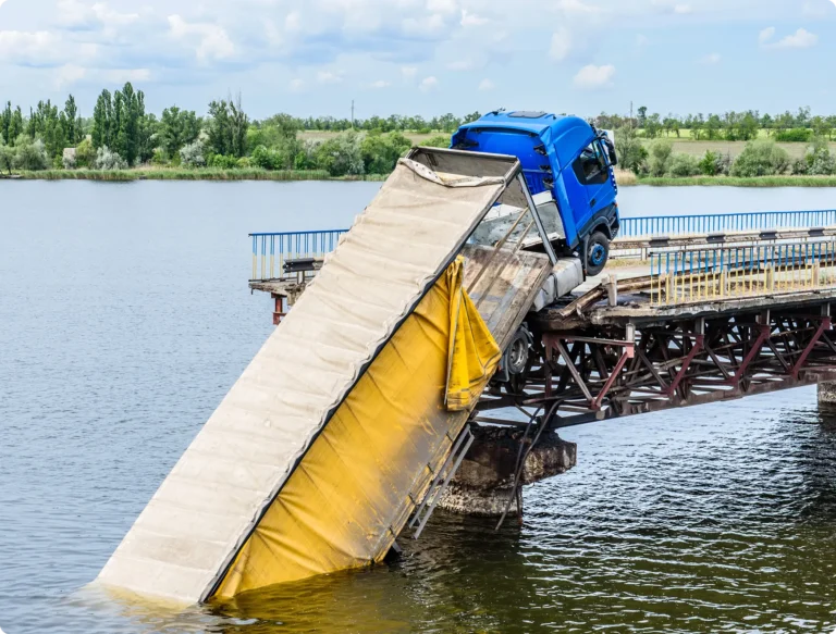 Truck with front end on bridge and rear hanging in water