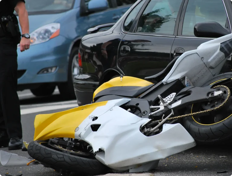 Motorcycle laying on ground next to a car